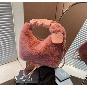 Detailed view of plush pink handbag with soft faux fur texture and pleated leather handle