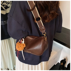 Brown Boston bag with a wide colorful strap and a cute plush bear charm detail