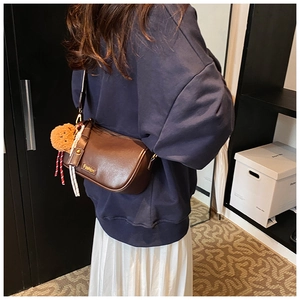 Detail showing dark brown Boston bag with Fashion label and bear charm on model