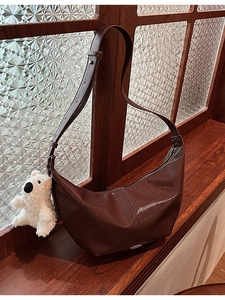 Deep brown crescent hobo bag with teddy charm on a retro wooden window sill