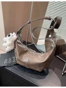 Deep brown leather half-moon crossbody bag with adjustable strap and plush bear charm
