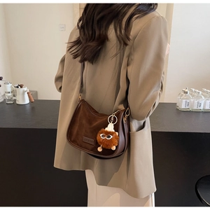 Détail d'un sac bandoulière en daim marron avec un charmant pendentif en peluche
