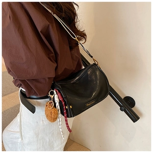 Fashionable black Boston bag detail featuring glossy finish and plush bear charm decoration