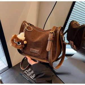 Détail du petit sac carré marron mat avec logo en cuir et charm peluche monstre