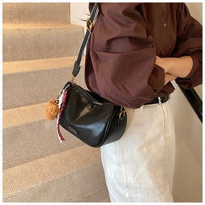 Detail of black Boston crossbody bag with plush bear charm and striped fabric strap