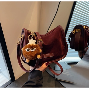 Détail du sac demi-lune bordeaux en daim avec bandoulière et breloque en peluche