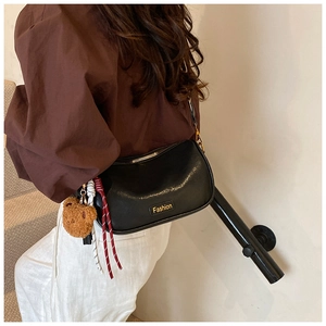 Detail of black leather Boston bag featuring yellow Fashion text and a bear charm