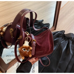 Détail du sac bandoulière en velours bordeaux avec poignée cuir et gri-gri peluche