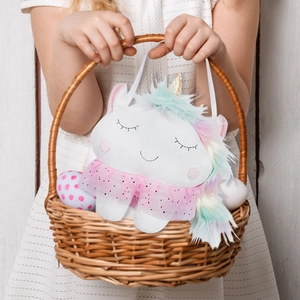 Unicorn plush toy in a basket with Easter eggs for kids gift and holiday decor