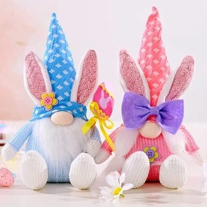 Detail of pink and blue Easter gnomes with rabbit ears and knitted hats on floral background