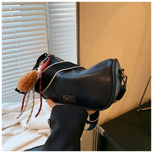 Detail of black Boston bag featuring metal Fashion plate and colorful charms