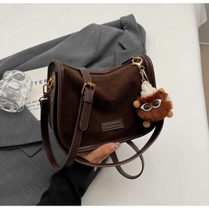 Détail du sac vintage en daim marron avec logo miao & she et pendentif peluche monstre