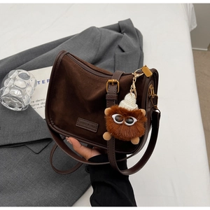 Détail du sac bandoulière vintage en daim marron avec bandoulière et porte-clés peluche