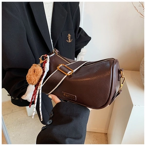 Detail view of brown leather Boston bag with fashion label and bear charm pendant
