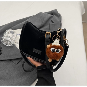 Détail du sac bandoulière en velours noir avec bandoulière en cuir et pompon en peluche
