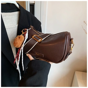 Detailed shot of dark brown Boston bag with wide canvas strap and fashion bag charms