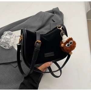 Détail du sac à bandoulière en velours noir avec zip doré et breloque peluche marron