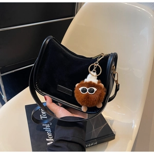 Détail du sac demi-lune en daim noir avec un joli pendentif monstre en peluche marron
