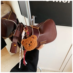 Close-up of brown leather Boston bag with fashion hardware and cute bear charm detail