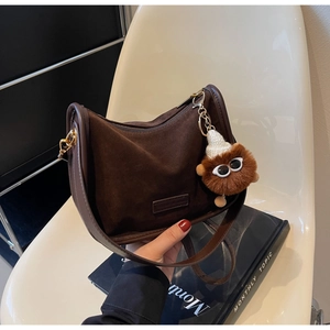 Détail du sac bandoulière en daim marron avec chaîne dorée et pendentif en peluche