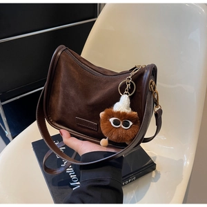 Détail d'un sac à bandoulière vintage marron foncé en daim avec breloque peluche