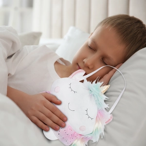 Peluche licorne fée des dents avec fourrure colorée tenue par un garçon qui dort