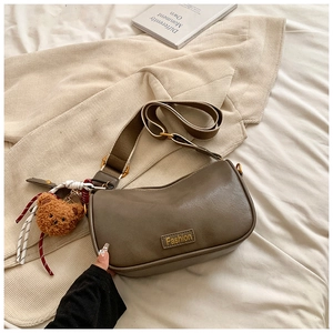 Detailed macro view of the brown moon bag with fashion tag and plush bear charm