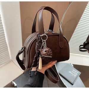 Detail van vintage bruine Boston tas met aardbeienhanger en dubbele ritssluiting