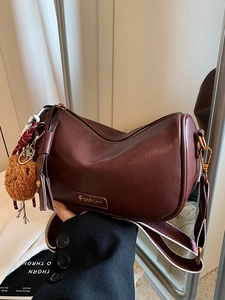 Deep brown Boston crossbody bag with decorative bear pendant and textured leather finish