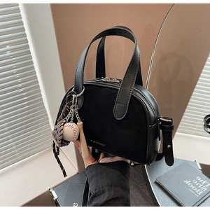 Detail van zwarte leren handtas met suède textuur, merklogo en baseball hangers