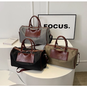 Close-up of three large travel bags in grey, black, and khaki with leather details