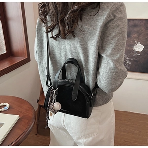 Detail van zwarte crossbodytas van leer met een baseballhandschoen-hanger