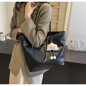 Detail of black tote bag with white stitching and plush cloud charm for urban commuting