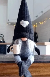 Detail view of a sitting coffee gnome plush with a knit hat and white mug decoration