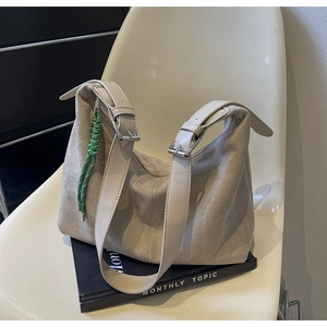 Detail of beige suede bucket bag with adjustable wide strap and green woven ornament