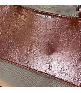 Close-up of brown crinkled leather texture and A Bag A NOCO golden logo engraving