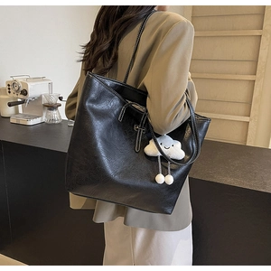 Detailed view of black tote bag with white contrast stitching and plush cloud charm decor