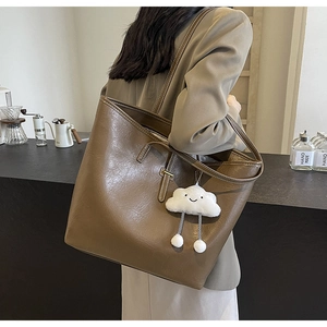 Detail of dark brown lychee texture leather tote bag with a cute white cloud plush pendant