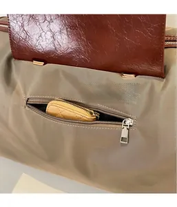 Detail of travel bag showing exterior zipper pocket with fabric and leather texture