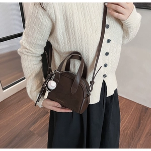 Gedetailleerd overzicht van een trendy bruine crossbodytas met honkbalbedel op model