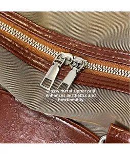 Detail of smooth metal dual zipper pullers on a brown leather large travel bag