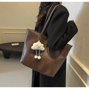 Close-up of deep coffee tote bag featuring white contrast stitching and plush cloud charm