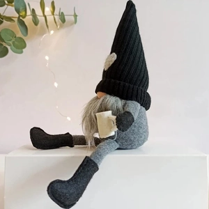 Detail of a sitting coffee gnome plush with knitted hat and heart patch holding a cup
