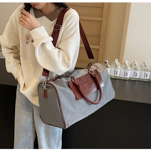 Detail of grey travel bag with brown leather trim and detachable shoulder strap
