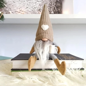 Close-up of a Christmas coffee gnome with a brown knit hat and heart patch on a book