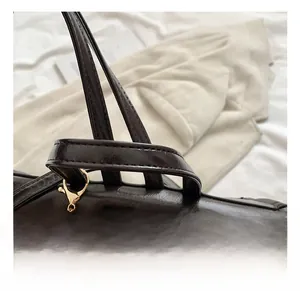 Detailed close-up of glossy leather handle with gold hardware and plush ball charm