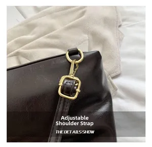Close-up of golden metal buckle and adjustable leather strap on dark brown vintage backpack