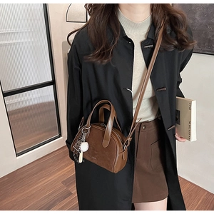 Detail van bruine leren Boston-tas met suède patchwork en baseball-tassel accessoire