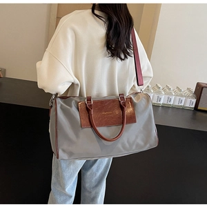 Detail of grey nylon travel bag with brown leather handles and adjustable shoulder strap