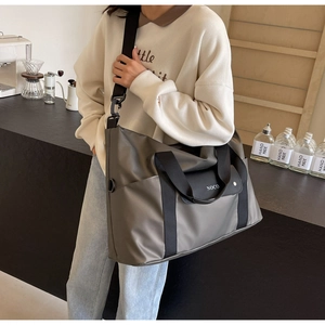 Borsa da viaggio in nylon grigio scuro con tracolla nera spessa indossata dal modello
